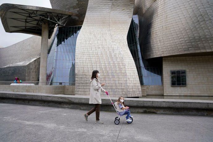 Una madre pasea con su hija en las afueras del Museo Guggenheim en Bilbao.