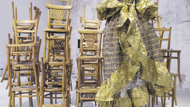 DESVELOS. La instalación transmite un clima de fin de fiesta. Sobre una serie de sillas, hay un vestido hecho con papeles de caramelos.