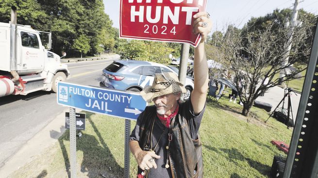 QUEJA. “Caza de brujas”, dice el cartel que sostiene un simpatizante de Donald Trump cerca del penal en el que ayer debió comparecer el expresidente republicano.