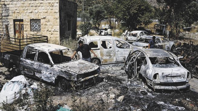 CAOS. Los palestinos revisan los vehículos quemados después del ataque de los colonos israelíes cerca de Ramalá en la Cisjordania ocupada por Israel.