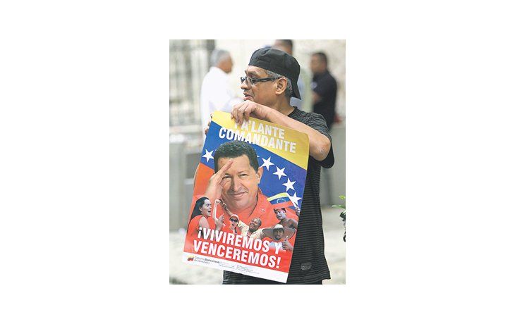 Un simpatizante exhibe un póster de apoyo a Hugo Chávez antes de la misa del domingo celebrada en La Habana para pedir por su recuperación. Su caso es una excusa para una ampliación de la tolerancia religiosa en la isla.