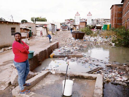 precariedad. Una mujer recoge agua en la barriada de Alexandra, cerca de Johanesburg. Más allá de toda su importancia, el final del régimen de segregación racial en Sudráfica aún no resuelve las desigualdades sociales.
