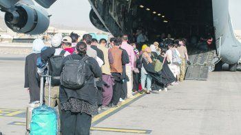 MAREA HUMANA. Un nutrido grupo de afganos en busca de refugio hace fila para abordar un avión C-17 Globemaster en el aeropuerto de Kabul. La evacuación de las familias de personas vinculadas a la ocupación occidental de Afganistán continúa a pesar de los tropiezos.