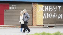 CONTROL. Un tanque ruso ataca un blanco cerca de la zona industrial donde se refugian civiles en Mariúpol. En la ciudad, asediada desde febrero, aún habitan miles de personas. En la calle, se lee en las persianas bajas de un comercio “acá vive gente”.