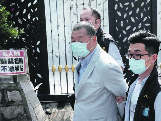 CENSURA. El prominente editor de medios Jimmy Lai sale esposado y rodeado de policías de la sede de uno de sus diarios en Hong Kong.