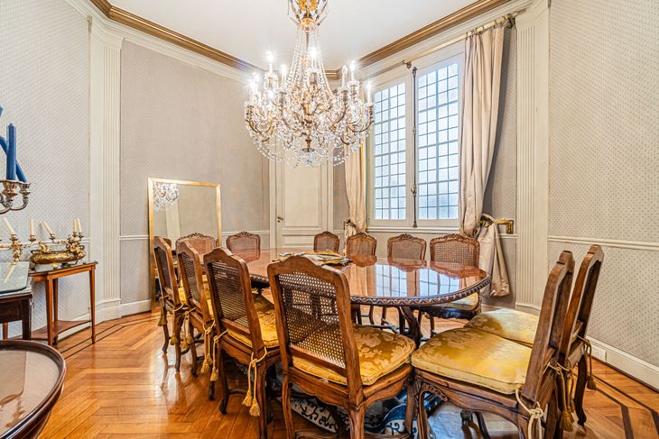 El comedor principal conserva la boiserie, los pisos de madera y una gran araña de cristal, en línea con la arquitectura y el estilo original El comedor principal conserva la boiserie, los pisos de madera y una gran araña de cristal, en línea con la arquitectura y el estilo original
