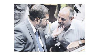 Mohamed Mursi dialoga el domingo con un directivo de la televisión oficial, poco antes de su primera declaración como presidente electo.