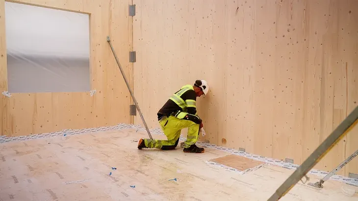 Un operario instala paneles estructurales mediante el sistema CLT (madera contralaminada), base del esquema constructivo del proyecto Un operario instala paneles estructurales mediante el sistema CLT (madera contralaminada), base del esquema constructivo del proyecto