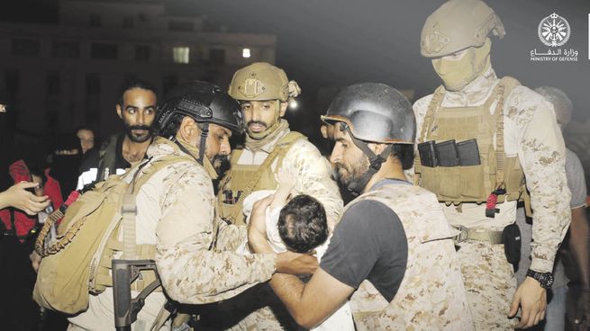 CONTRA RELOJ. Militares sauditas ayudan a un bebé a llegar a un barco que sacará a su familia de Sudán.