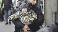 DRAMA HUMANITARIO. Un policía ucraniano carga a un niño en momentos en que residentes de la ciudad de Lviv se concentraban en la estación de trenes para huir a Polonia.