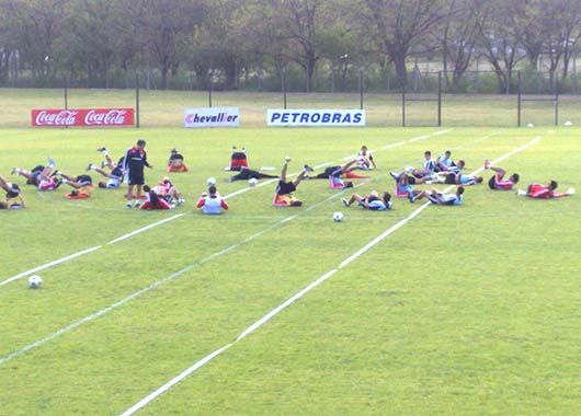 Sincronizados. Todos con las piernas arriba, los jugadores elongan y terminan el entrenamiento.