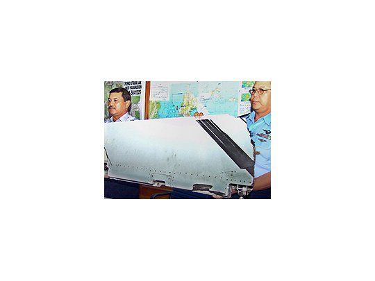 Miembros del servicio de rescate muestran la parte del avión hallada