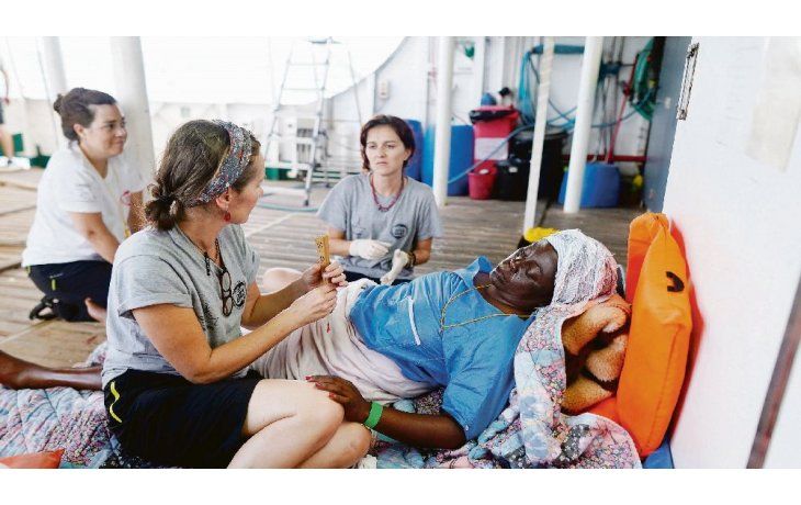 ámbito.com | ROSTROS. La camerunesa Josepha (izquierda), asistida en la cubierta del Open Arms. Chuol (derecha), de Sudán, se baña tras ser rescatado en el mar.