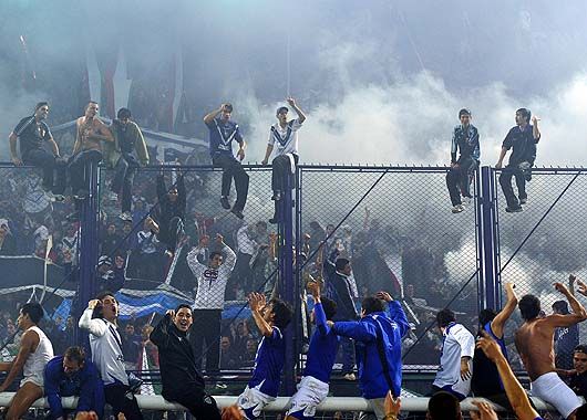 Los jugadores festejan con su hinchada sentados sobre el travesaño.