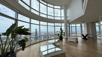 Living de grandes dimensiones en Puerto Madero con doble altura y ventanales curvos que ofrecen vistas panorámicas de la Ciudad y el río