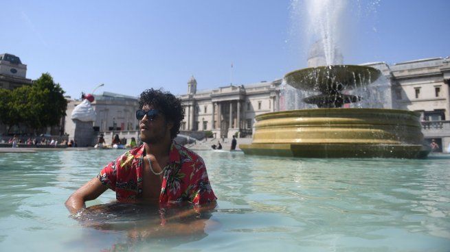 Un hombre se refresca en una fuente de Londres.