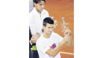 Djokovic celebra con su título en mano ante la desazón de Nadal. El español no pudo defender la corona en la Caja Mágica y ve cómo el serbio lo acecha semana tras semana.