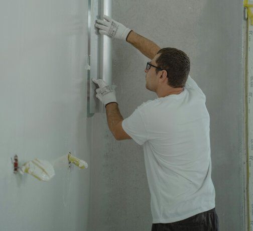 Un operario alisa la pared de la ducha de un baño en refacción Un operario alisa la pared de la ducha de un baño en refacción