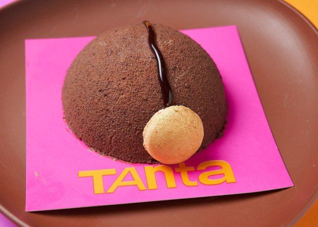 La Esfera de Chocolate, una combinación de mousse cremosa de chocolate amargo peruano, galletas de coco caseras, almendras garrapiñadas y toffe, todo decorado con un toque de chocolate amargo y macarons. La Esfera de Chocolate, una combinación de mousse cremosa de chocolate amargo peruano, galletas de coco caseras, almendras garrapiñadas y toffe, todo decorado con un toque de chocolate amargo y macarons.