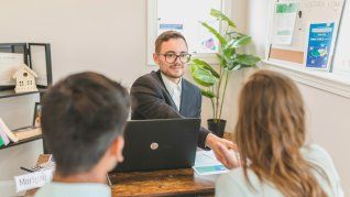 Un escribano felicita a los flamantes propietarios por la firma de hipoteca y entrega de la escritura a los titulares del inmueble Un escribano felicita a los flamantes propietarios por la firma de hipoteca y entrega de la escritura a los titulares del inmueble