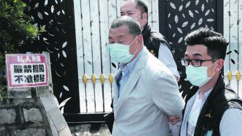 CENSURA. El prominente editor de medios Jimmy Lai sale esposado y rodeado de policías de la sede de uno de sus diarios en Hong Kong.