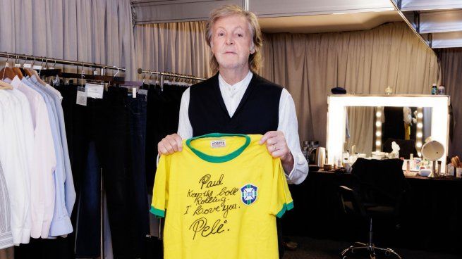 Paul McCartney posando con la camiseta firmada por Pelé.