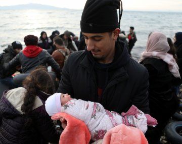 Un migrante sostiene en brazos a una bebé recién nacida.