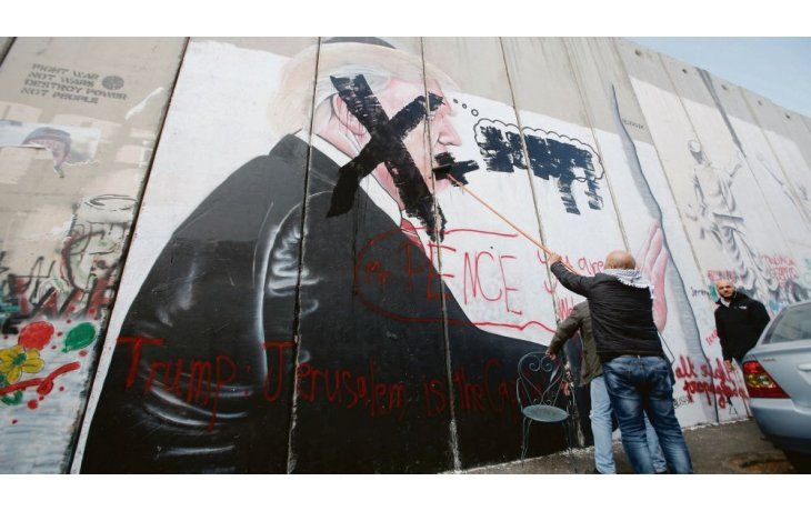 ámbito.com | RECHAZO. Un palestino tacha una imagen de Donald Trump en el muro que divide a Israel con Cisjordania.