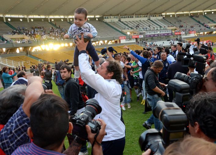 Pedro Troglio levanta a su hijo en forma de festejo.