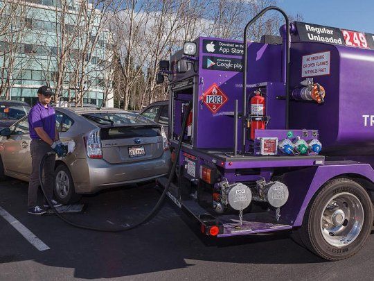 La empresa Booster Fuels suministra combustibles con sus exclusivos camiones de color púrpura para llenar los tanques de los autos mientras sus dueños están trabajando.