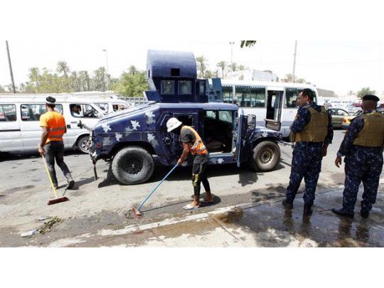 Un grupo de trabajadores del estado iraquí limpiando el lugar donde el suicida del Estado Islámico cometió el atentado.
