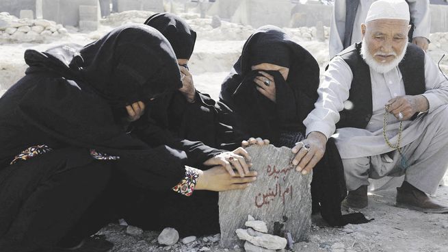 DESCONSUELO. Los familiares de Um al-Banin, una de las chicas que perdió la vida en la masacre, rezan en su tumba en Kabul.
