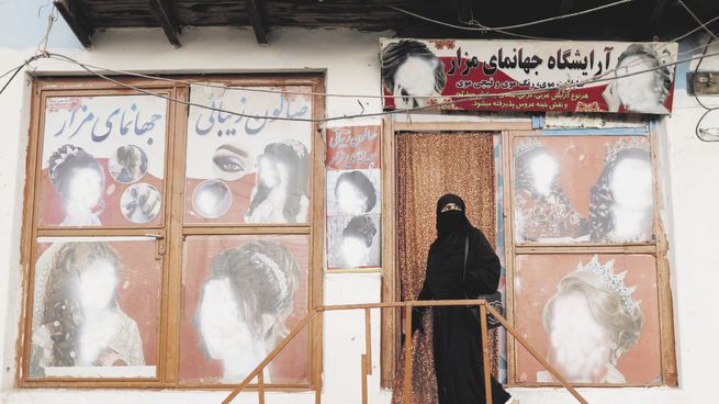 CANCELADAS. Una mujer ingresa a un salón de belleza en Kabul cubierta por el niqab. Las imágenes del exterior debieron ser veladas por orden de los talibanes, que ahora directamente prohiben esos negocios.