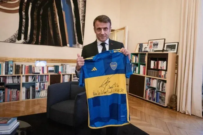 Emmanuel Macron posando con una camiseta autografiada por Javier Milei.