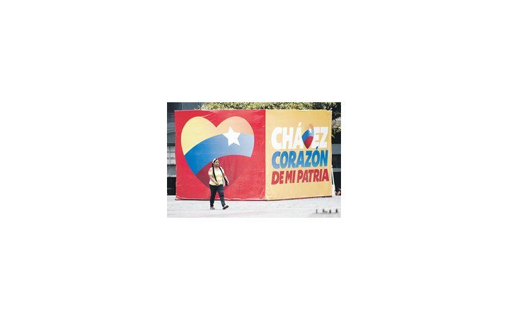 Una mujer camina delante de un cartel proselitista de Hugo Chávez. Otro sondeo le da una ventaja superior a 30 puntos, pero uno apunta un empate.