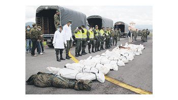 Policías y soldados colombianos custodian los cuerpos de los rebeldes de las FARC abatidos en un operativo sobre la frontera con Ecuador. Un niño apareció entre las víctimas.