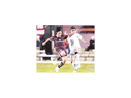 Mauro Camoranesi lucha con Mario Bellone. El veterano volante fue clave en el triunfo de Lanús en Santa Fe.