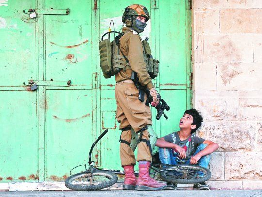 OCUPACI&Oacute;N. Un soldado israel&iacute; junto a un ni&ntilde;o palestino en Hebr&oacute;n.