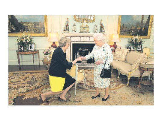 TRADICIÓN. Theresa May le hace una reverencia a la reina Isabel II, que ayer la confirmó como primera ministra de un Reino Unido que enfrenta un futuro de turbulencias.