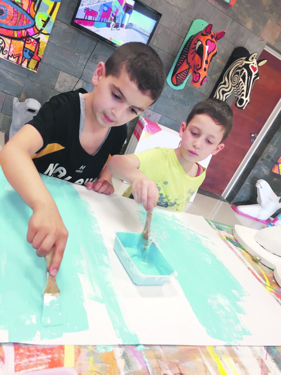 integración. Joudi y Mikl pintan una bandera argentina, mientras Jouni (arriba) y la pareja de Lana y Majb posan para las cámaras de Ámbito Financiero, en la municipalidad de Estancia Grande, en San Luis.