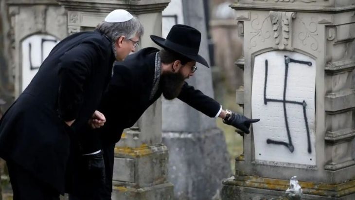 Two men check a desecrated Jewish grave in the Strasbourg cemetery, France. Two men check a desecrated Jewish grave in the Strasbourg cemetery, France.