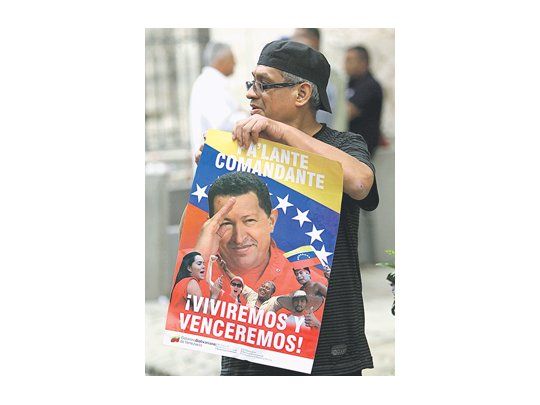 Un simpatizante exhibe un póster de apoyo a Hugo Chávez antes de la misa del domingo celebrada en La Habana para pedir por su recuperación. Su caso es una excusa para una ampliación de la tolerancia religiosa en la isla.