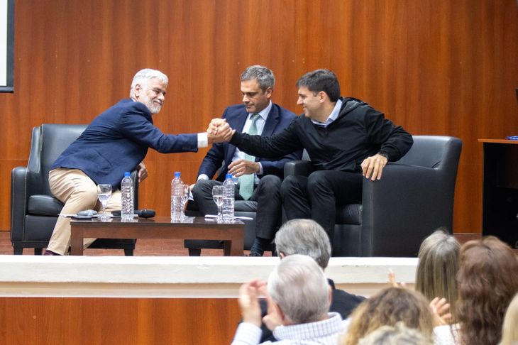 Roberto Felleti estrecha manos con Diego Bossi. En el medio, Guillermo Michel, el moderador.