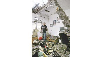 ámbito.com | Un israelí mira los destrozos provocados por un cohete de Hizbollahen su casa de Nahariya. Los ataques sobre esa ciudaddejaron ayer un muerto.