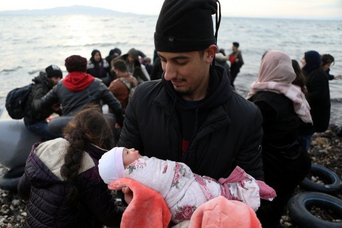 Un migrante sostiene en brazos a una bebé recién nacida.