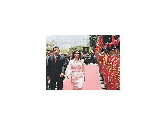 Cristina de Kirchner camina junto a Hugo Chávez, con un looken el que predomina el rosado, color que connota paz, perotambién romanticismo y dulzura.