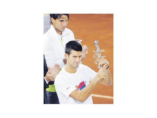 Djokovic celebra con su título en mano ante la desazón de Nadal. El español no pudo defender la corona en la Caja Mágica y ve cómo el serbio lo acecha semana tras semana.