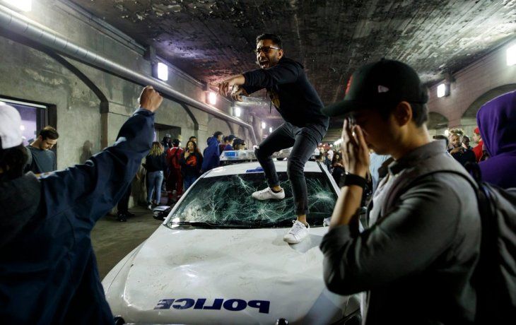 Un hincha de Toronto Raptors trepado a un patrullero de la policía durante los festejos por el título de la NBA.