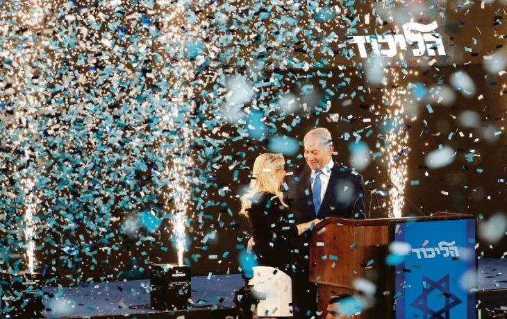 FESTEJO. Bibi Netanyahu, anoche, en medio de confetti, junto a su esposa Sara. Confía en que el escrutinio final le dé el triunfo y le permita seguir en el poder.