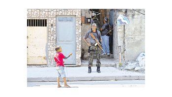 Un niño remonta un barrilete cerca de un policía en el Morro do Alemao, una de las favelas recuperadas por el Estado. La presencia policial-militar se extenderá por siete meses.